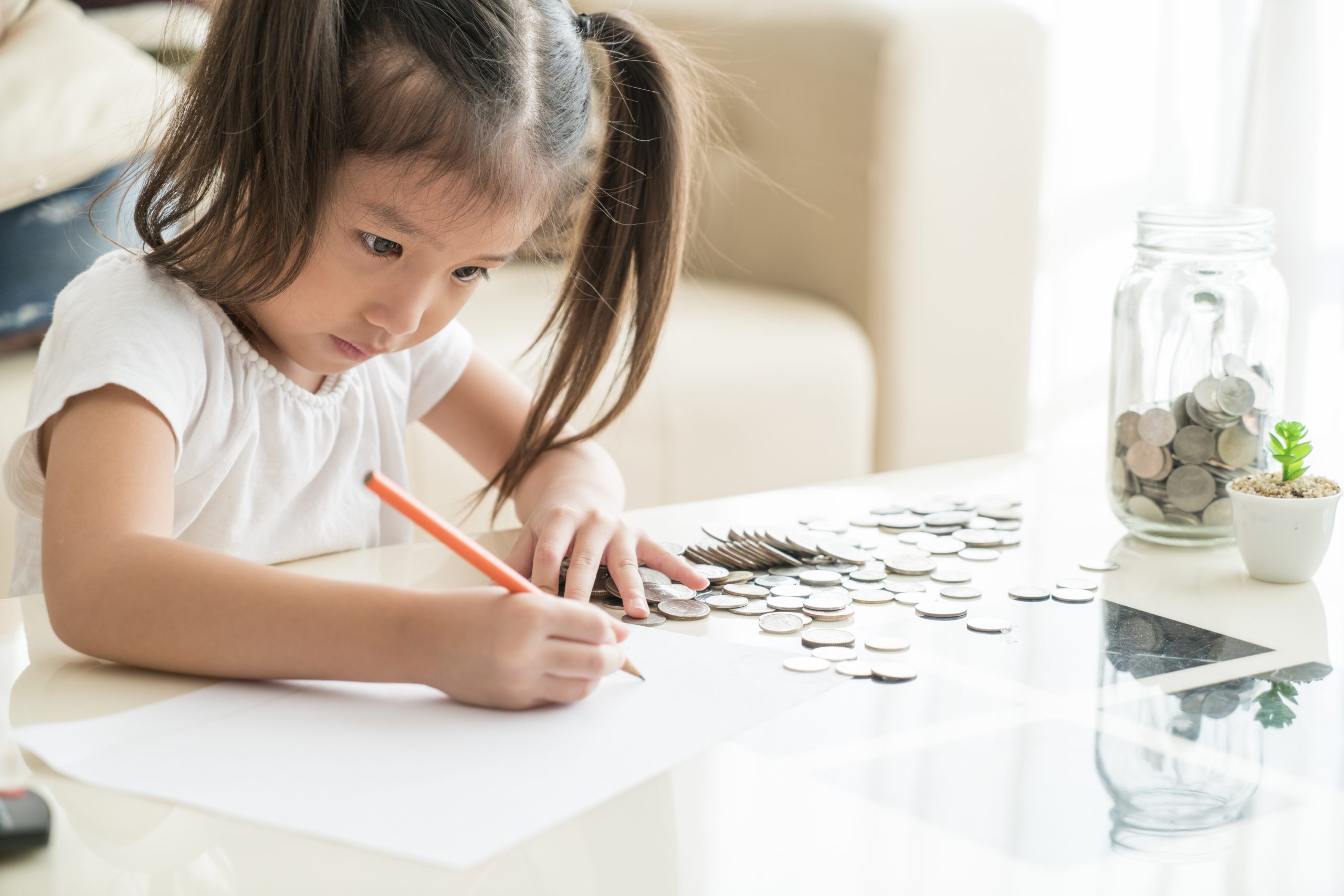 Asian,Cute,Girl,Saving,Money,Putting,Coins,Into,Glass,Bank,