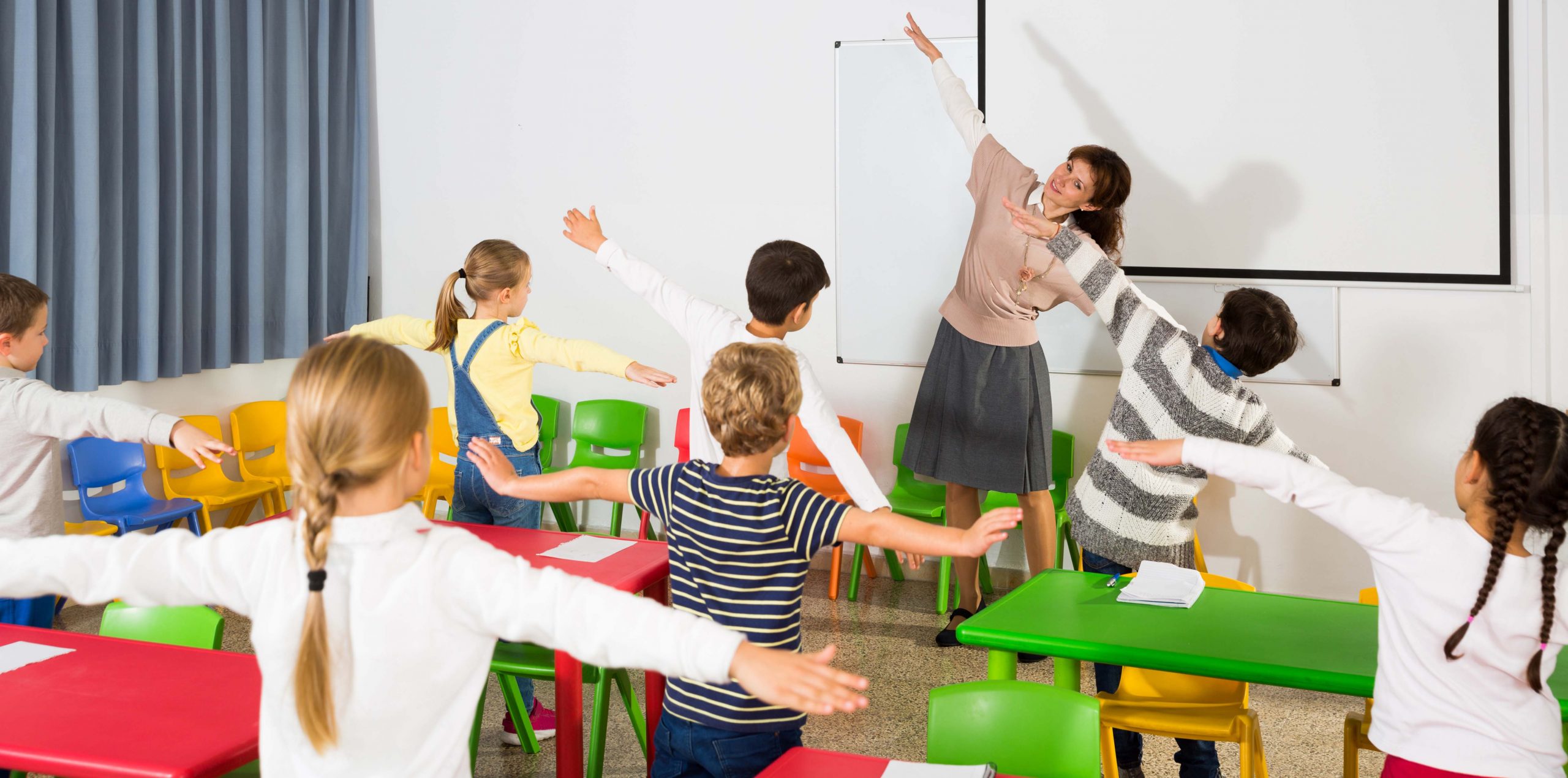 Young,Friendly,Female,Teacher,Conducting,Little,Warm-up,With,Pupils,During