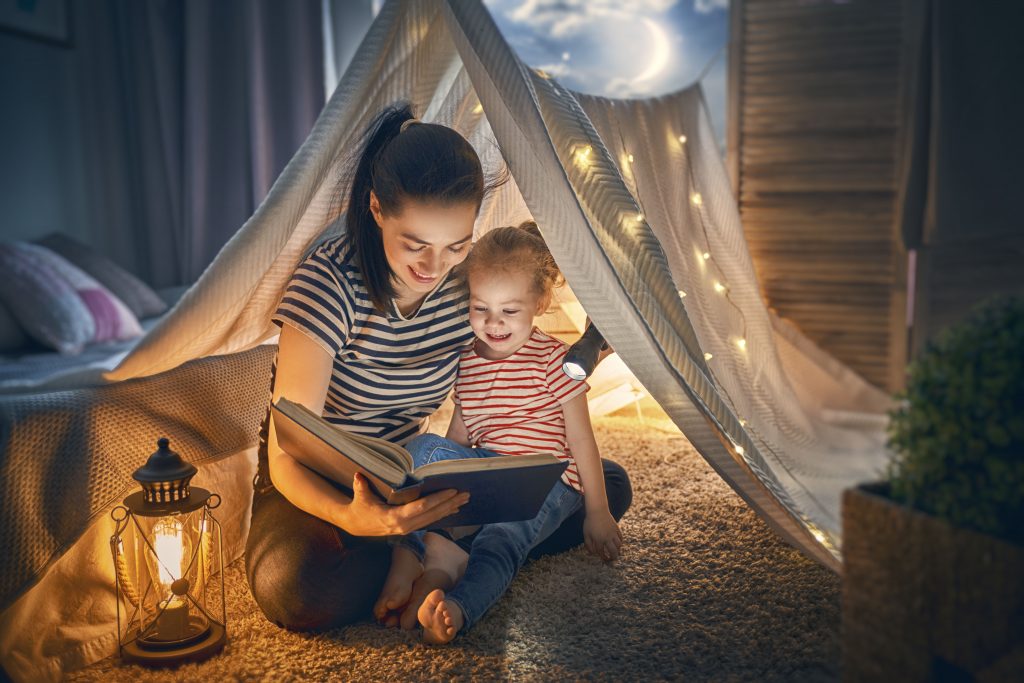Family,Bedtime.,Mom,And,Child,Daughter,Are,Reading,A,Book การอ่านหนังสือให้เด็กฟังเป็นการสร้างบริบทให้เด็กเห็น<br />
ความเชื่อมโยงระหว่างพยัญชนะกับเรื่องราว<br />