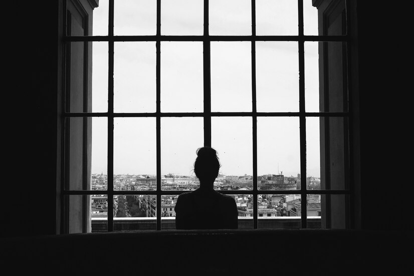 black-white-shot-lonely-female-standing-front-windows-looking-buildings_181624-26508 ความเหงา