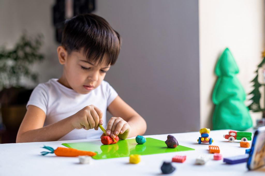 Small boy playing with plasticine IKEA Effect